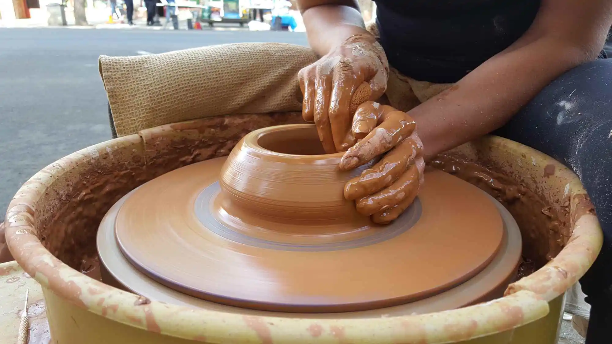 Close-up of hands sculpting a clay pot on a pottery wheel